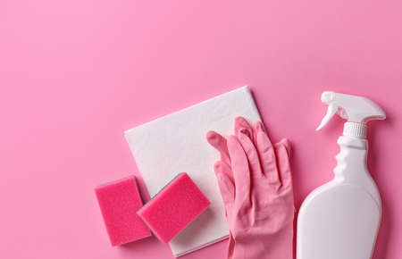 White spray bottle, rubber gloves, sponges and cleaning cloth on pink background, top viewの写真素材