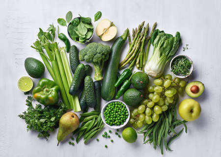 Beautiful composition of various healthy green fruits, vegetables and herbs on white rustic table, top view. Apple, pear, grapes, avocado, peas, celery, pepper, lime, asparagus, zucchini, cucumber, broccoli, spinach, parsley and micro greensの写真素材