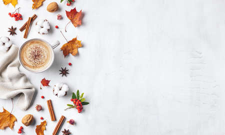 Beautiful autumn compositionon on white background. Hot coffee, dried leaves, knitted blanket, cotton flowers and rowan berries. Top view. Copy space.の写真素材