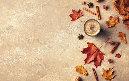 Beautiful autumn flat lay composition on beige background. Hot coffee, dried leaves, knitted blanket and spices. Top view. Copy space.の写真素材