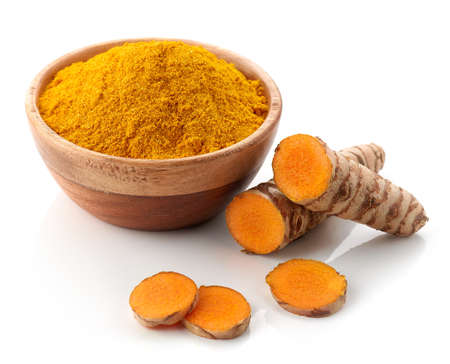 Bowl of turmeric powder and fresh whole and sliced root isolated on white backgroundの写真素材