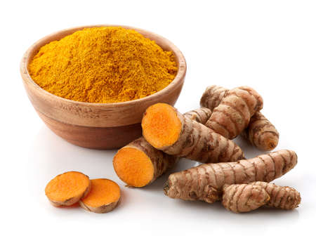 Bowl of turmeric powder and fresh whole and sliced root isolated on white backgroundの写真素材