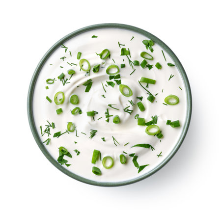 Green ceramic bowl of sour cream dip sauce with fresh herbs isolated on white background, top viewの写真素材