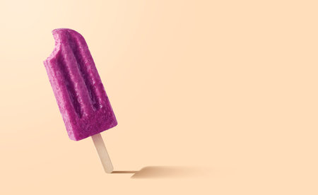 Bitten purple fruit and berry ice cream on pastel orange background. Blueberry and raspberry flavor. Empty space for textの写真素材