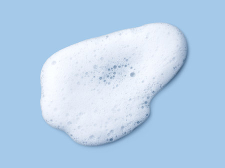 White skincare cleansing foam on light blue background. Soap, shampoo or shower gel foam texture, close-up, top viewの写真素材