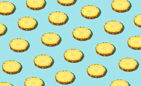 Colorful pattern of fresh ripe pineapple slices. Minimal trendy sunlight fruit concept on light blue backgroundの写真素材
