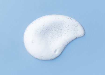 White skincare cleansing foam on light blue background. Soap, shampoo or shower gel foam texture, close-up, top viewの写真素材