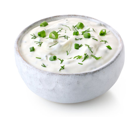 White ceramic bowl of fresh sour cream dip sauce with herbs isolated on white backgroundの写真素材