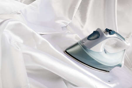 Electric iron ironing white satin fabricの写真素材