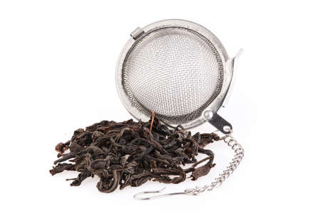 Black tea, and tea strainer with chain, isolated on a white background. A black tea and tea strainer is a close-up.の写真素材