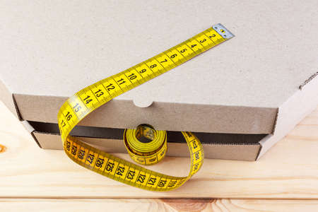 Yellow rag tape measure and pizza box. The concept of proper nutrition and weight loss.の写真素材