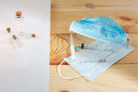 Medical protective mask with syringes on a wooden background. Corona virus. Healthcare and medical...