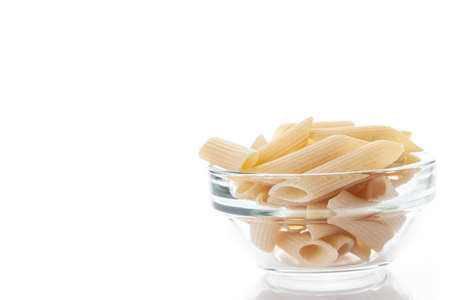 Raw feathers macaroni in bowl. Italian pasta close-up, isolated on the white background.の写真素材