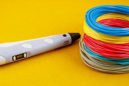 3d pen, and kit of colorful PLA or ABS plastic filament on yellow background. close up