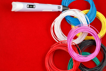 3d pen, and kit of colorful PLA or ABS plastic filament on red background. close up