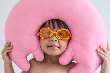 Little girl preparing to go swimming with pink pillows on the head の写真素材