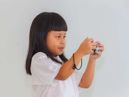 Happy little girl photographer doing photos with still camera on whiteの写真素材