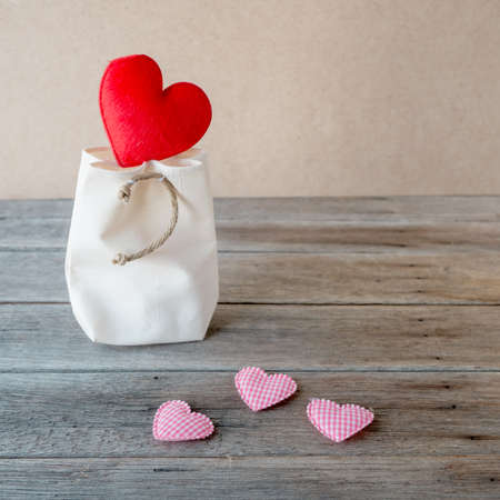 Red heart on white bag, pink hearts pattern on wooden table,の写真素材