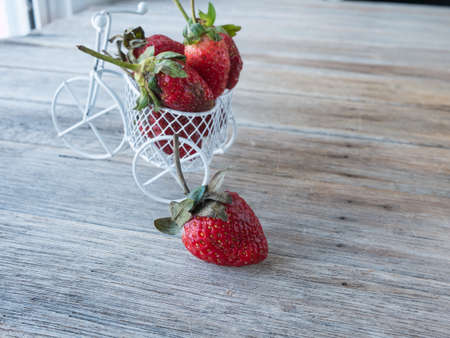 Strawberry on strawberry in bicycle toy, strawberry dry out on wooden tableの写真素材