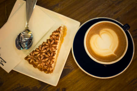 Blurred image Hot coffee late art in black cup on table, defocused image cake in plate,の写真素材