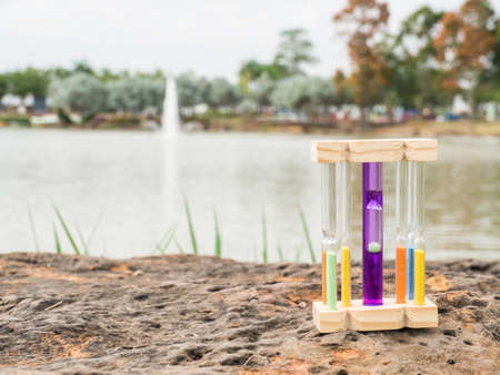 Hourglass on stone and blurred lake background,