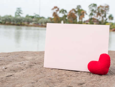 Red heart and paper card on rock retro background, blurred lake background,の写真素材