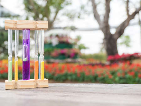 Hourglass on wooden table, blurred flower background,の写真素材