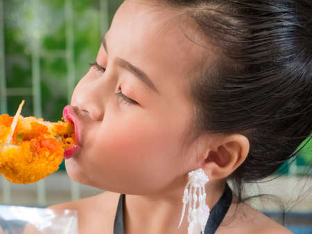 Cute little Girl eating the delicious fried chickenの写真素材
