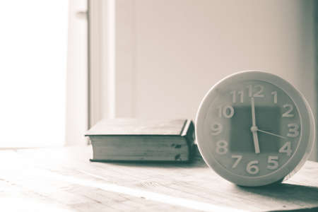 green alarm clock on table, light enters house, blur old book on table, image vintage and retro,の写真素材