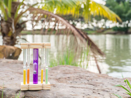 Hourglass on stone and blurred lake background,の写真素材