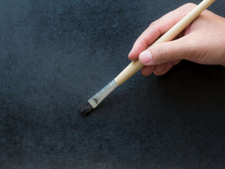 Artist paints a picture in hand with palette close up.