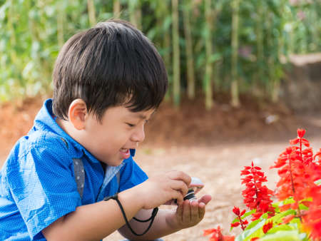 Little asian boy take camera on garden flower,の写真素材