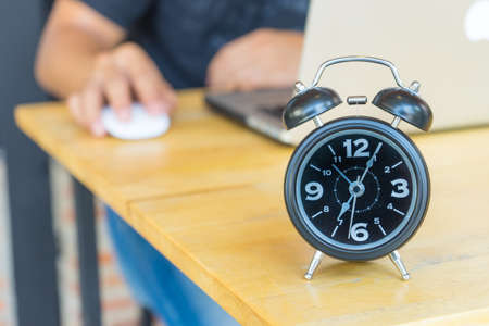 Alarm clock on table with blurred business man,
