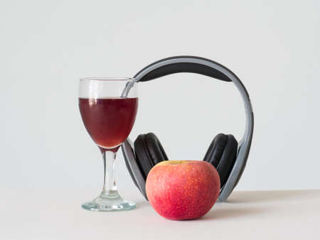 wine apple in glass with black hreadphone on white background,