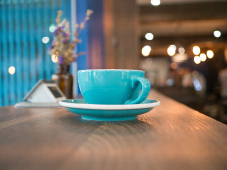 Blue coffee cup on table, light bokeh background,