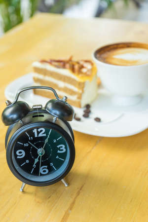 Alarm clock on table with blurred hot coffee background,の写真素材