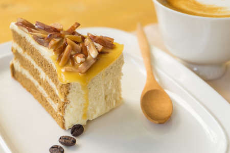 Defocused Hot coffee late in white cup on blurred raw coffee seed background, Bakery almond in...