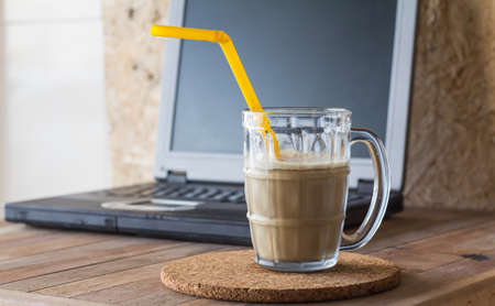 Cold coffee in cup on notebook background,