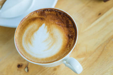 hot coffee late in white glass on wooden table,