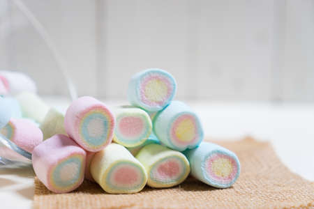 Color marshmallows on sack with white wooden background,の写真素材