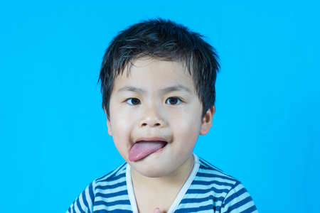 Asian cute boy with Tongue stick on blue background, chocolate dirty mouth,の写真素材
