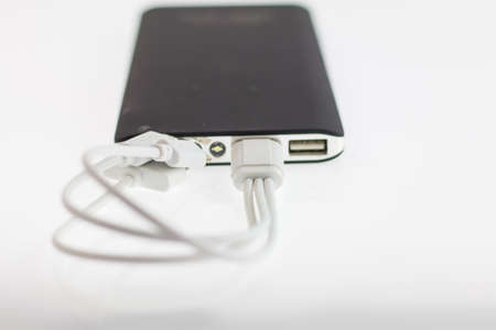 White jack insert power bank, blured black power bank on white background, power bank have dust in...