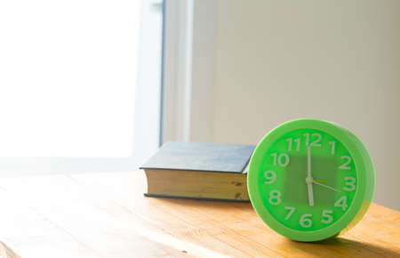 green alarm clock on table, light enters house, blur old book on table,の写真素材