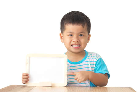 Little boy holding white board on table and white background, a cute asian boy,の写真素材