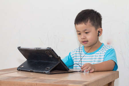 Children are viewing tablet on wooden table, dirty wall background,の写真素材
