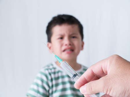 little boy looking crying syringe on white background,の写真素材