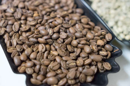 Raw seed coffee in black tray, focus select color brown raw coffeeの写真素材