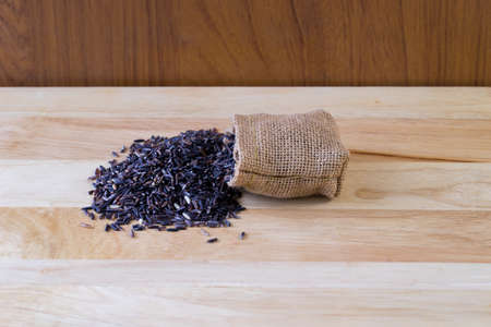 Riceberry rice in sack on wooden table,の写真素材
