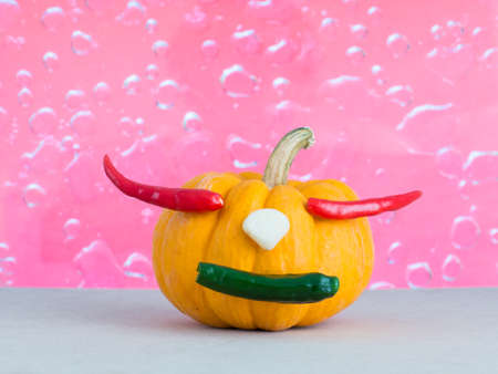 Pumpkin on pink drop water background, red chili in pumpkin, yellow pumpkin make mouth by green chili, garlic on yellow pumpkin,の写真素材