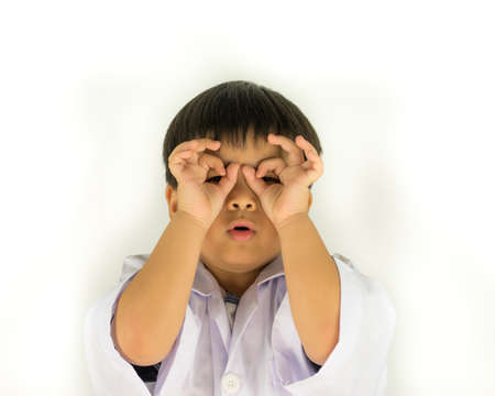 Portrait of a funny little boy looking at camera through fingers isolated on a white backgroundの写真素材